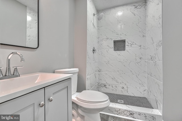 bathroom featuring tiled shower, vanity, and toilet