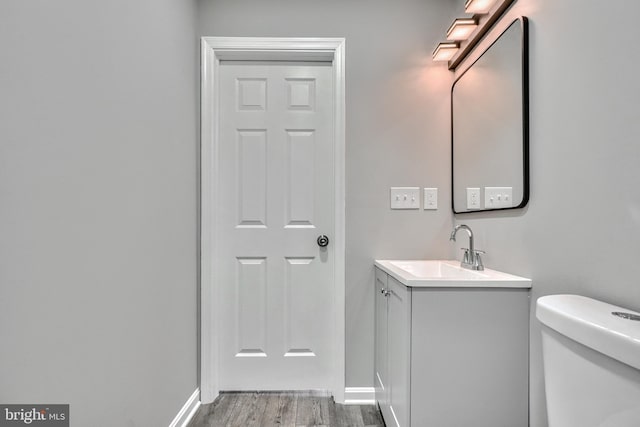 bathroom featuring wood-type flooring, toilet, and vanity