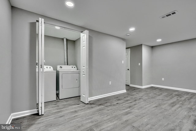 clothes washing area featuring washing machine and dryer and light wood-type flooring