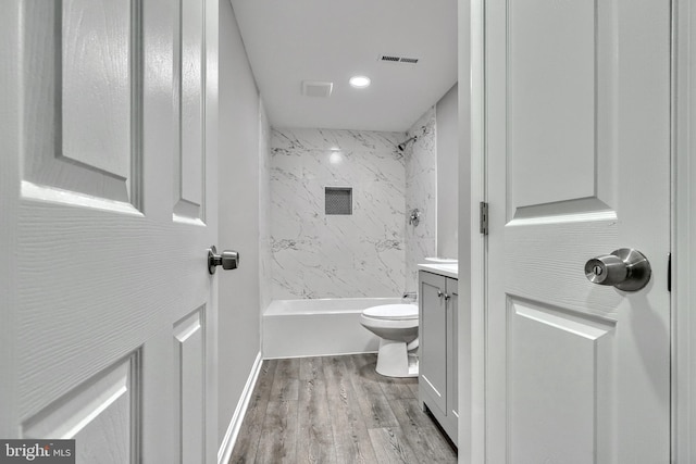 full bathroom featuring tiled shower / bath combo, vanity, hardwood / wood-style floors, and toilet