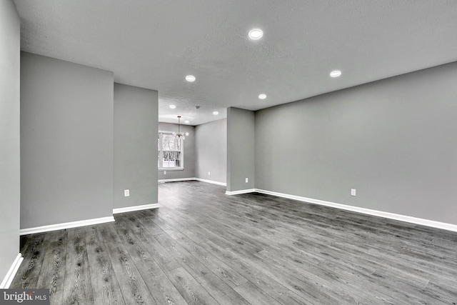 unfurnished room with an inviting chandelier, hardwood / wood-style floors, and a textured ceiling