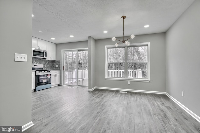 unfurnished dining area with a textured ceiling and light hardwood / wood-style floors