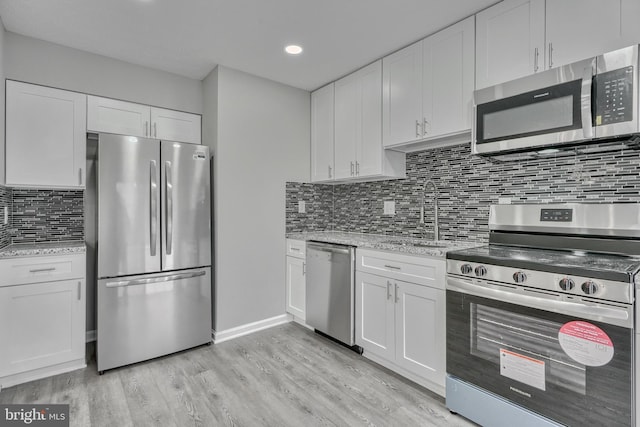 kitchen with appliances with stainless steel finishes, sink, light hardwood / wood-style flooring, and white cabinets