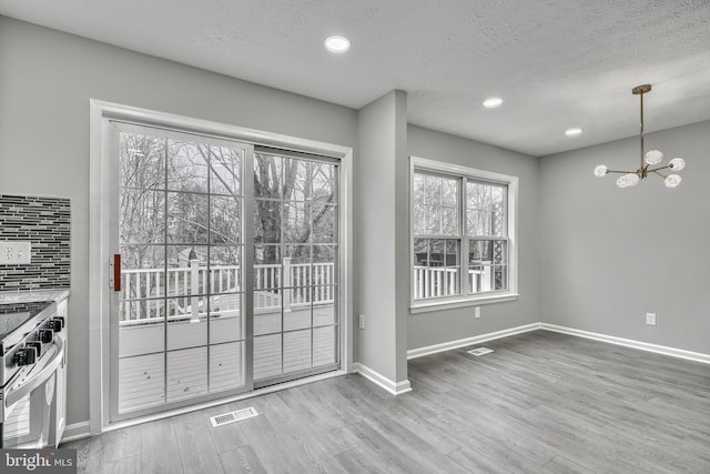 doorway featuring a notable chandelier, a textured ceiling, and light wood-type flooring