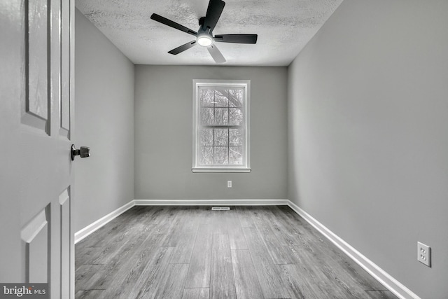 empty room with ceiling fan, a textured ceiling, and light wood-type flooring