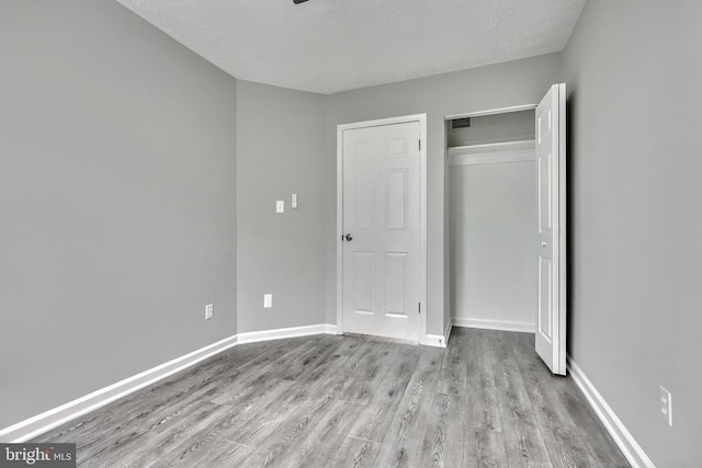 unfurnished bedroom with light hardwood / wood-style flooring, a closet, and a textured ceiling