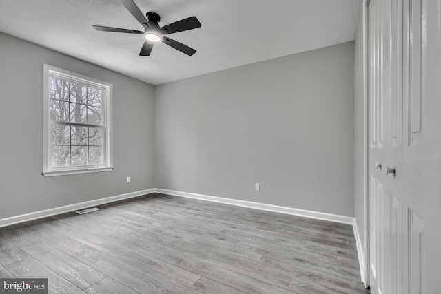 empty room with a textured ceiling, light hardwood / wood-style flooring, and ceiling fan