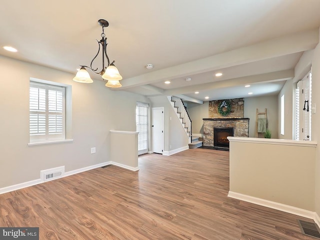 unfurnished living room featuring visible vents, a stone fireplace, baseboards, and wood finished floors