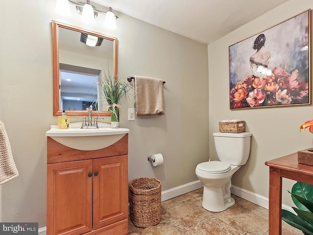 half bath featuring baseboards, vanity, and toilet