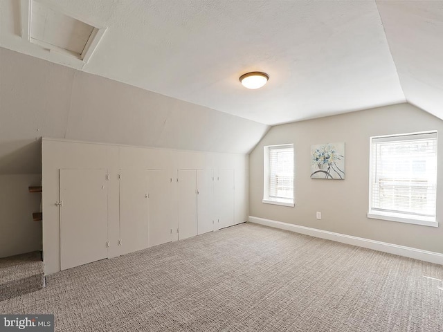 bonus room with lofted ceiling, baseboards, and light colored carpet