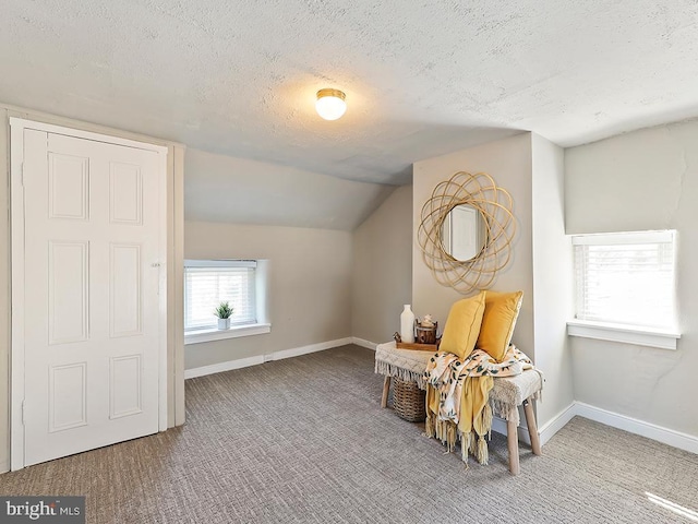 living area featuring carpet flooring, vaulted ceiling, a textured ceiling, and baseboards