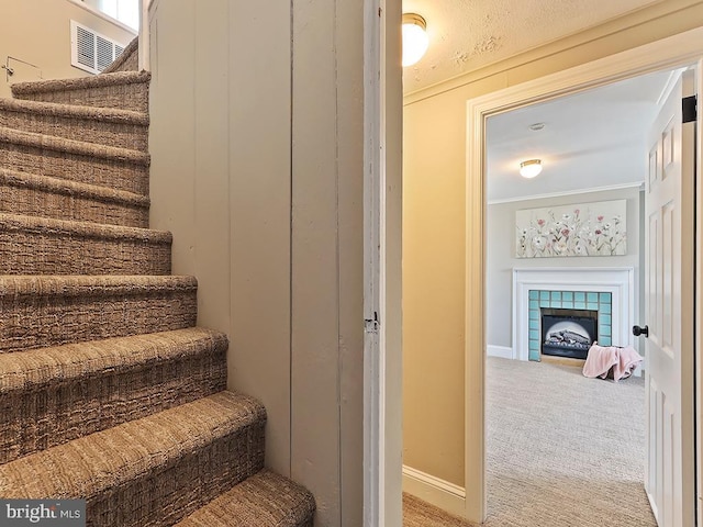 stairway featuring a tiled fireplace, carpet, and baseboards