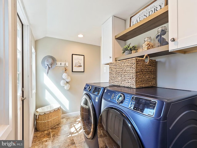 laundry area featuring washing machine and dryer, stone finish flooring, cabinet space, and baseboards