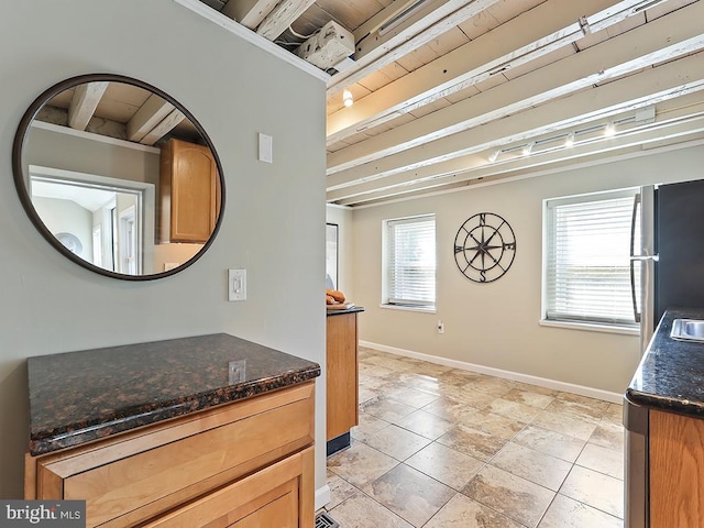 interior space with baseboards, beam ceiling, and freestanding refrigerator