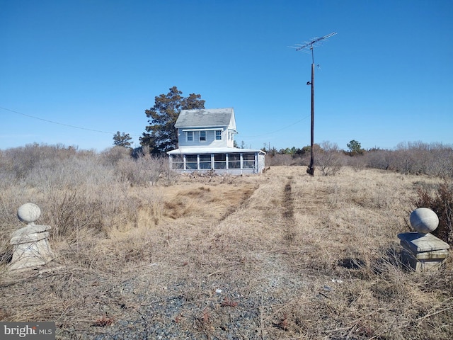 rear view of property featuring a rural view and a sunroom