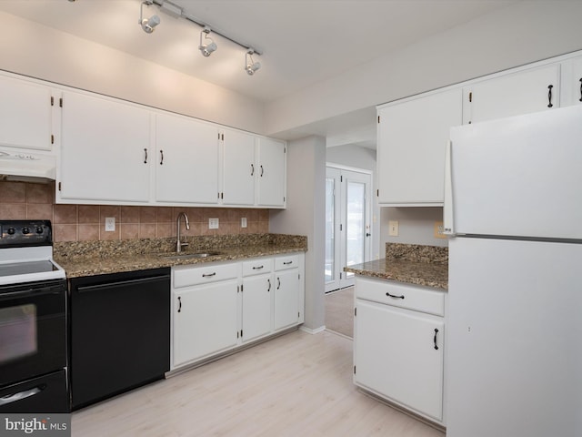 kitchen featuring dishwasher, electric range oven, dark stone countertops, freestanding refrigerator, and a sink