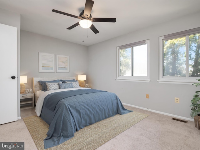 bedroom featuring baseboards, visible vents, ceiling fan, and light colored carpet