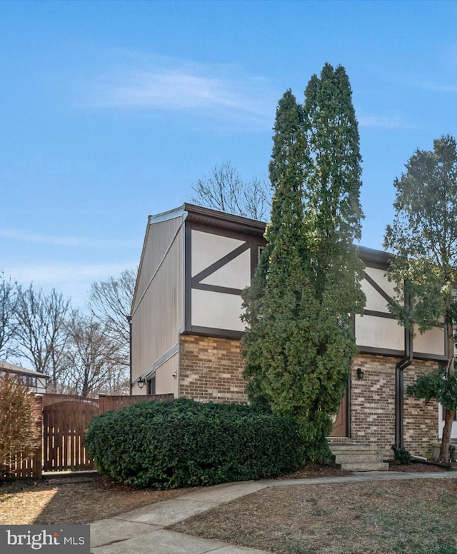 exterior space featuring brick siding, fence, and stucco siding