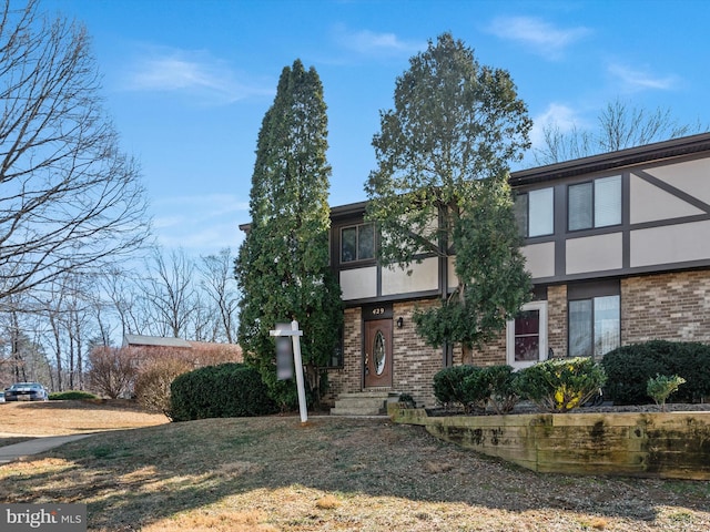 view of front facade with brick siding, a front lawn, and stucco siding