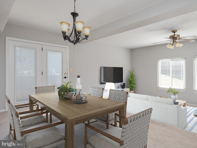 carpeted dining space featuring ceiling fan with notable chandelier