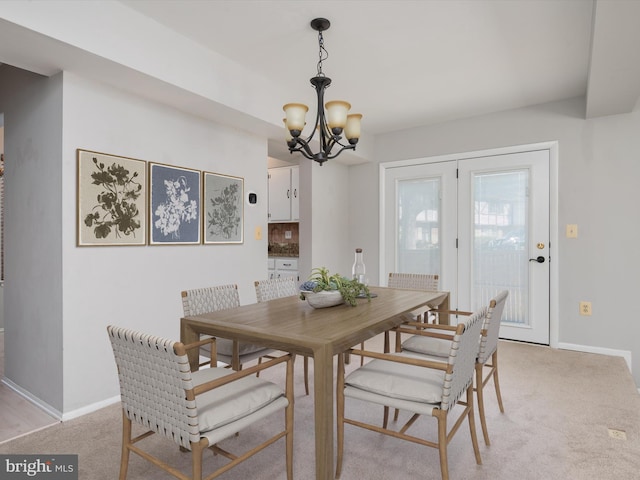 dining space with a notable chandelier, baseboards, and light colored carpet