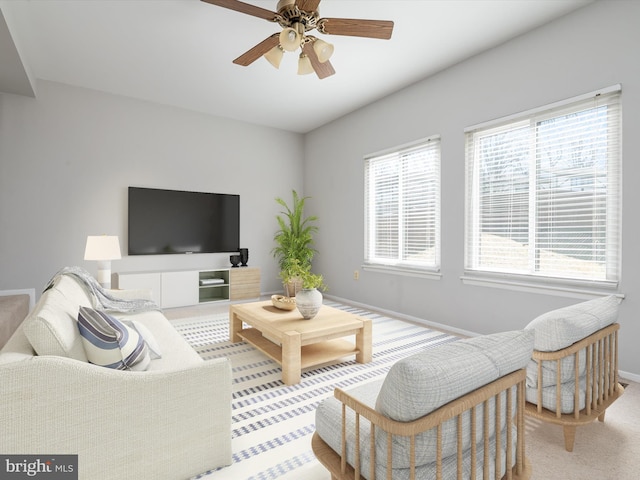 living area with ceiling fan, light colored carpet, and baseboards