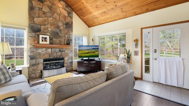 living room with wood-type flooring, a stone fireplace, plenty of natural light, and wooden ceiling