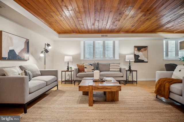 living room with wood ceiling, a healthy amount of sunlight, a tray ceiling, and light hardwood / wood-style floors