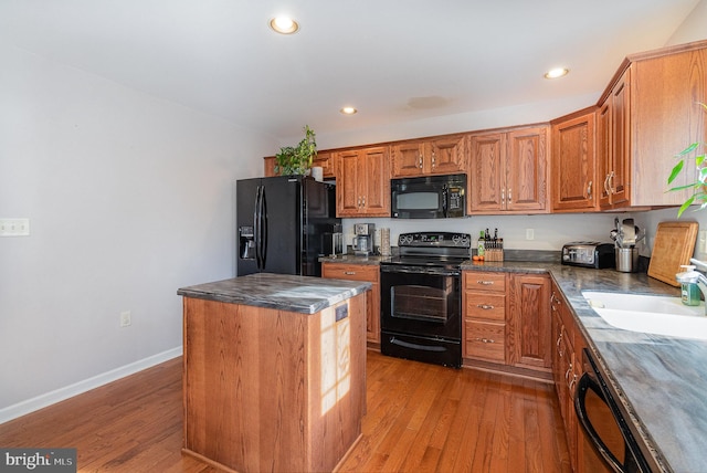 kitchen featuring hardwood / wood-style flooring, a center island, sink, and black appliances