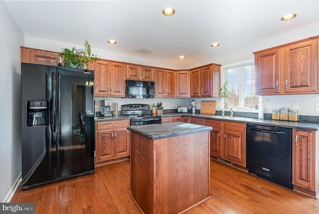 kitchen with hardwood / wood-style flooring, black appliances, and a kitchen island