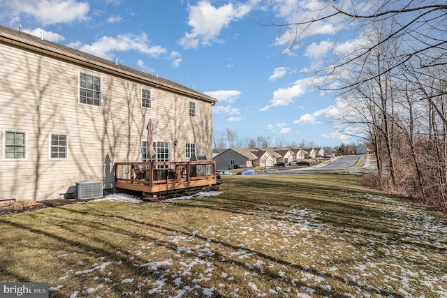 snow covered property with cooling unit, a deck, and a lawn