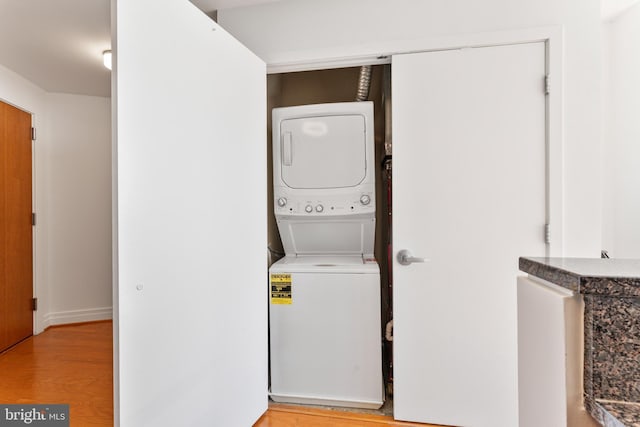 laundry room featuring stacked washer and dryer and light hardwood / wood-style floors