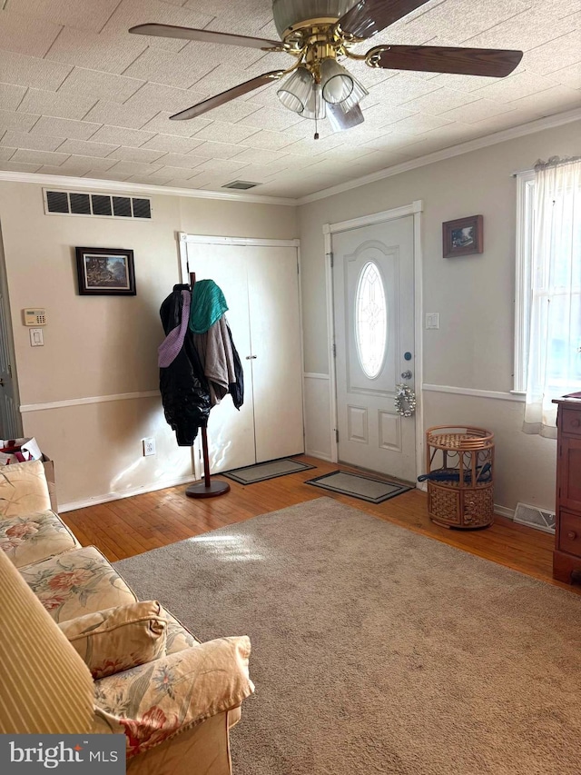 foyer with hardwood / wood-style flooring, ceiling fan, crown molding, and a wealth of natural light