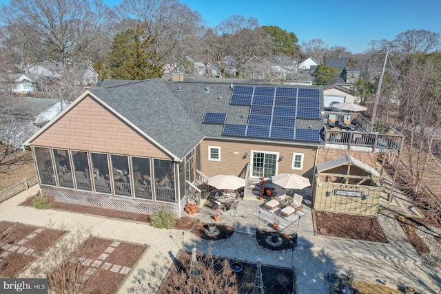 rear view of house featuring a patio, a sunroom, and solar panels