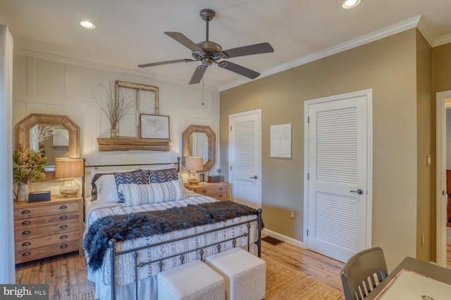 bedroom featuring crown molding, ceiling fan, two closets, and light wood-type flooring