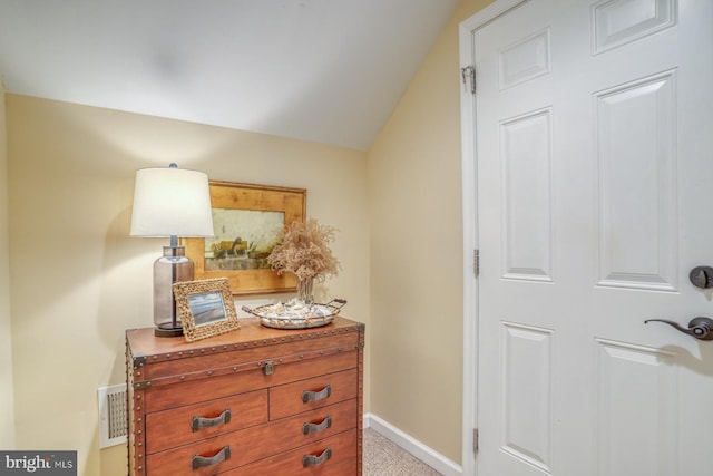 hallway with light colored carpet and vaulted ceiling