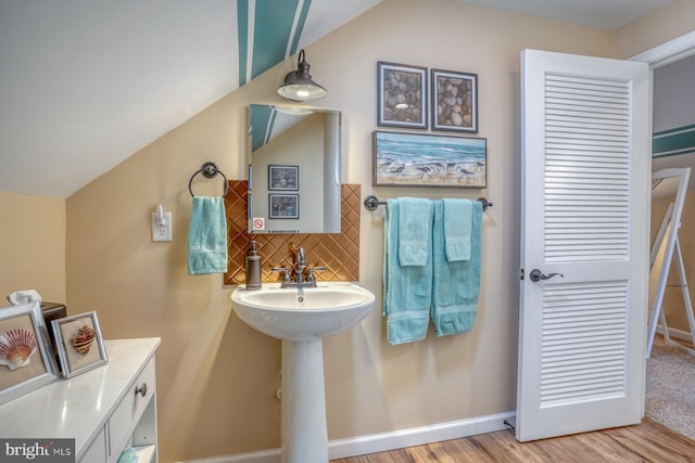 bathroom featuring sink, decorative backsplash, vaulted ceiling, and wood-type flooring