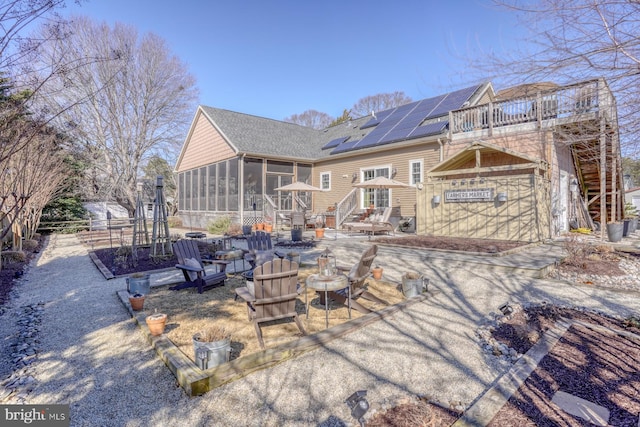 back of house with a sunroom and solar panels