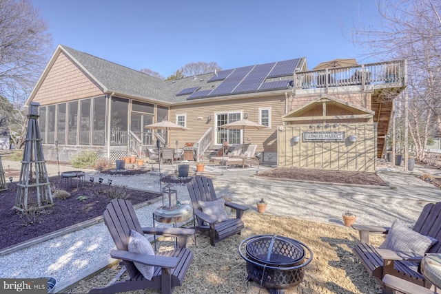 back of house featuring an outdoor fire pit, a patio, a sunroom, and solar panels