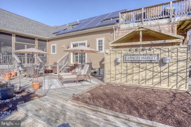 back of property with a balcony, a patio, a sunroom, and solar panels