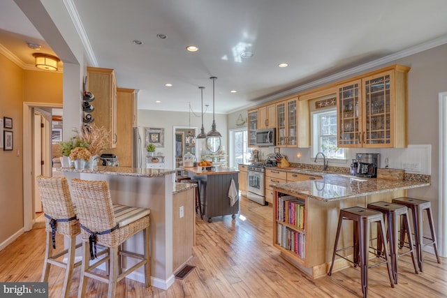 kitchen with a breakfast bar area, stainless steel appliances, a center island, light stone countertops, and kitchen peninsula