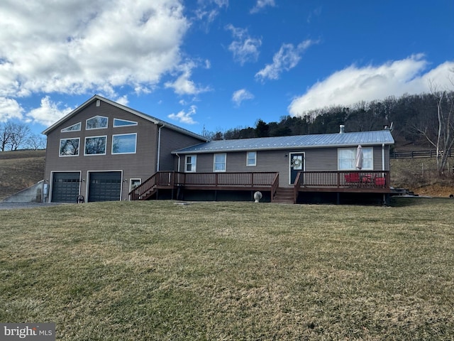 back of property featuring a lawn, an attached garage, and a wooden deck