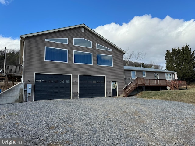 view of side of home with gravel driveway, a garage, stairs, and a deck