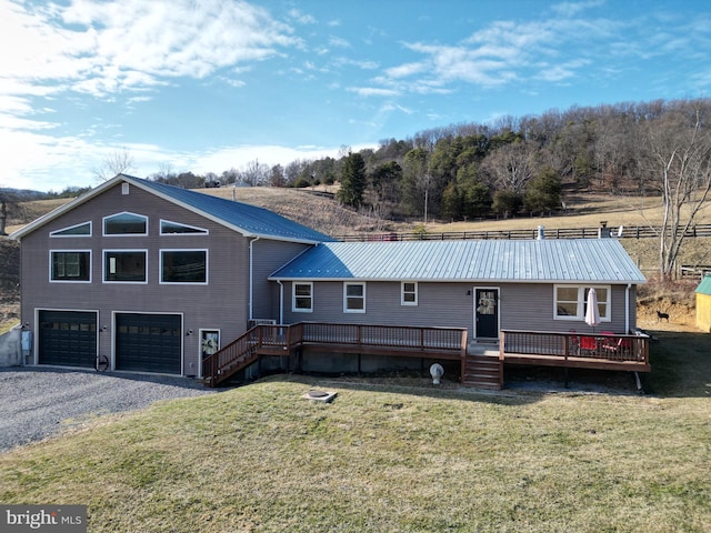 chalet / cabin with a front yard, metal roof, a deck, and an attached garage