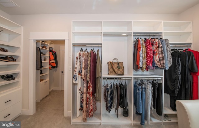 walk in closet featuring light carpet