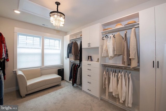 spacious closet with a chandelier and light carpet