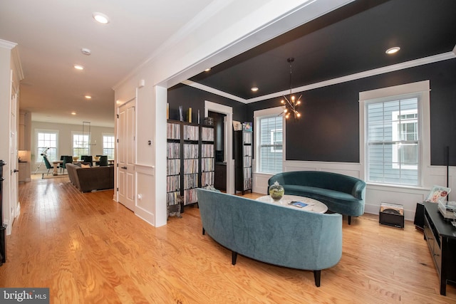 living room with crown molding, a notable chandelier, and light wood-type flooring