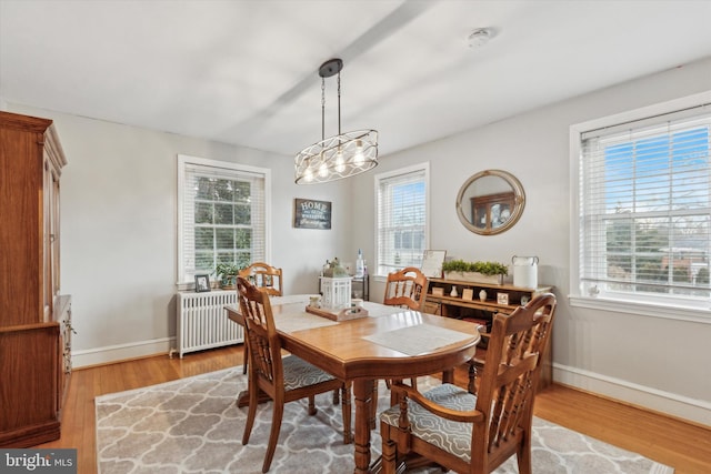 dining space featuring radiator heating unit, a chandelier, and light hardwood / wood-style flooring