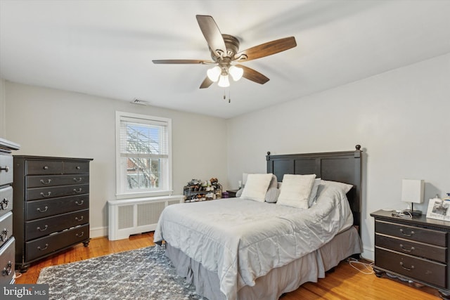 bedroom featuring ceiling fan, radiator heating unit, and light wood-type flooring