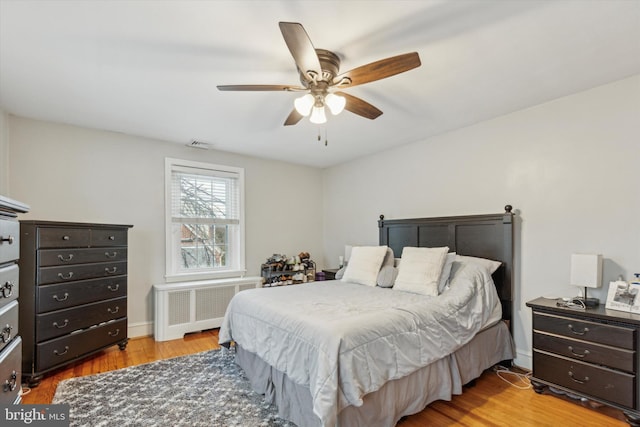 bedroom featuring radiator, light hardwood / wood-style flooring, and ceiling fan